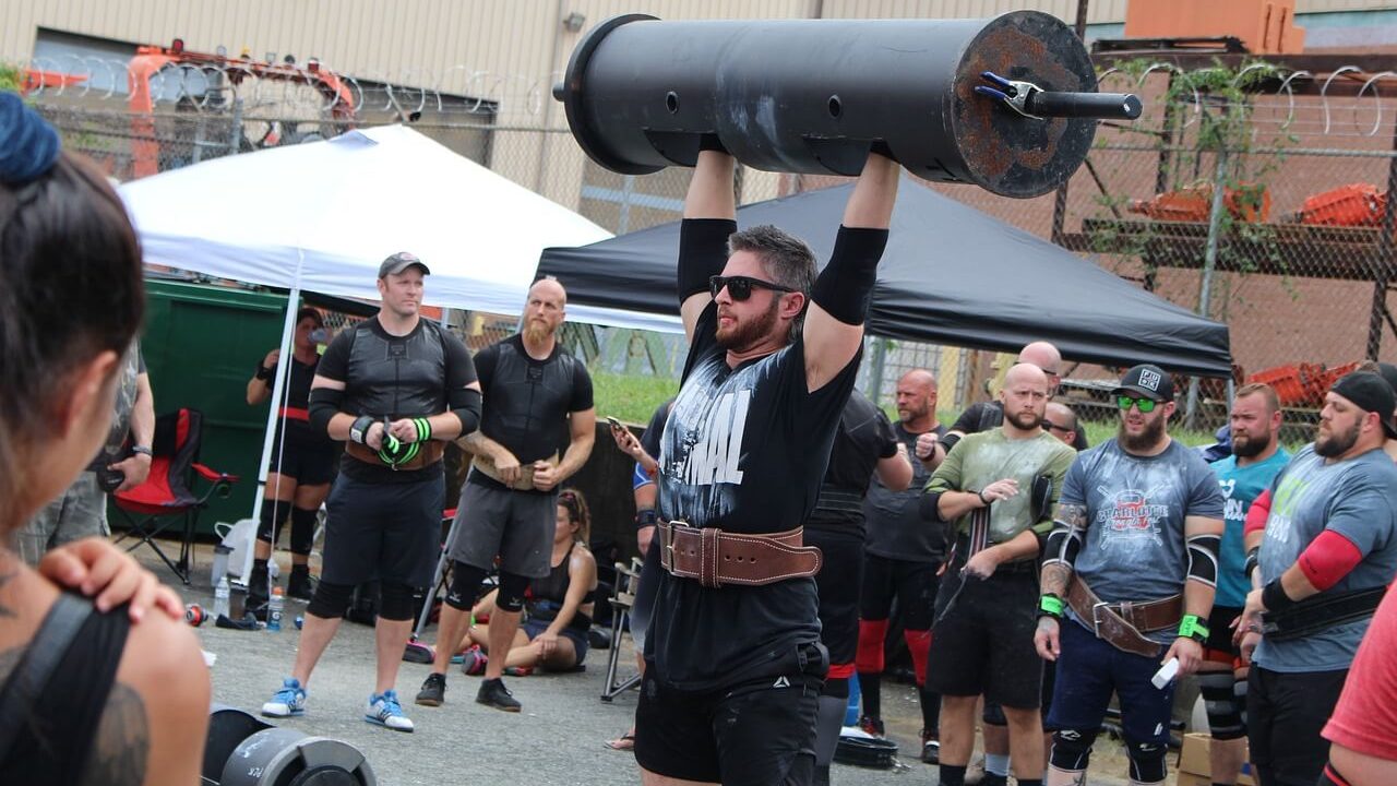 Alt text for an image of an athlete performing a log lift, a strongman exercise involving lifting a weighted log.